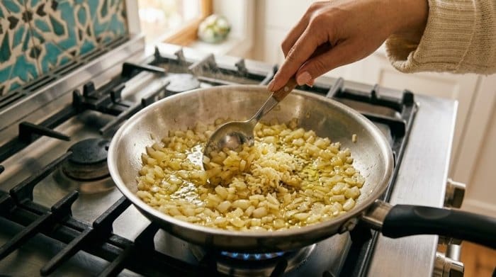 تفت دادن پیاز و در درون ماهیتابه برای تهیه سس گوجه